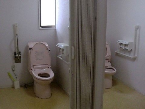 窓から明るい光の入るトイレは、清潔に保たれている。ピンク色の温水洗浄を備えた便器の横には、手すりを２か所設置していている。