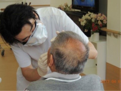 歯科医師から歯の検診を受けるために、口を開けているご入居者様