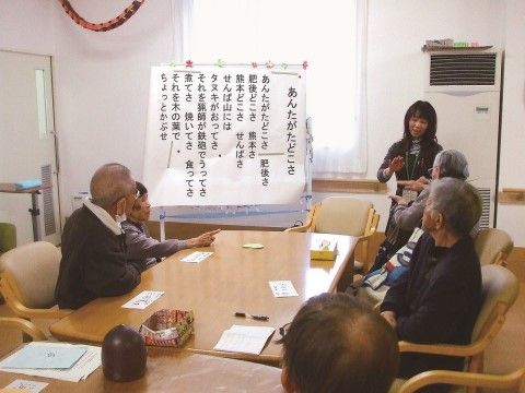 童謡の手遊びの仕方を、講師から学んでいるご入居者様