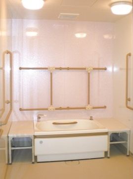壁面に多くの手すりがある。浴槽は足を伸ばして入れる広さがあり、浴槽内にも手すりがある。浴槽両脇に転落防止の台が設置されている。