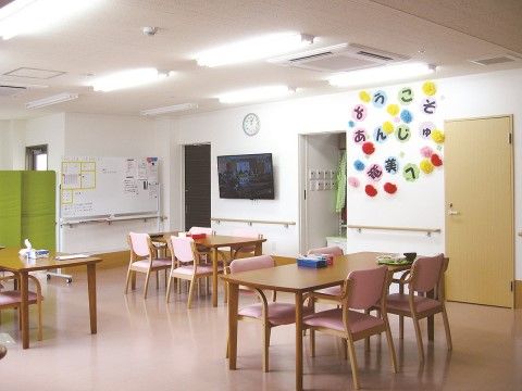 床面が木目調の明るい雰囲気で、木製のテーブルセットが3つある。大型テレビ、連絡用のホワイトボードが壁面に設置されている。