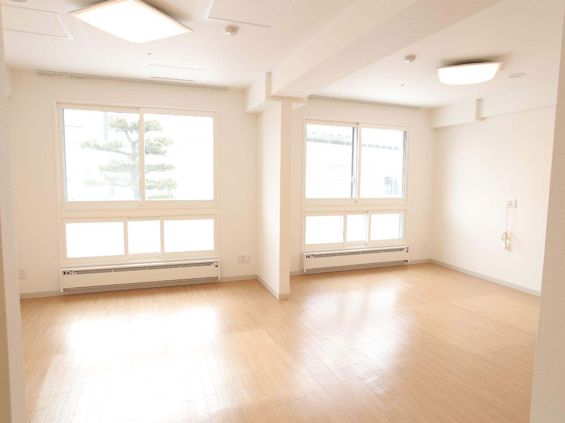 広い間取りの部屋は薄い色のフローリングが敷かれている。窓が2つあり、そこからは自然光が入るようになっている。
