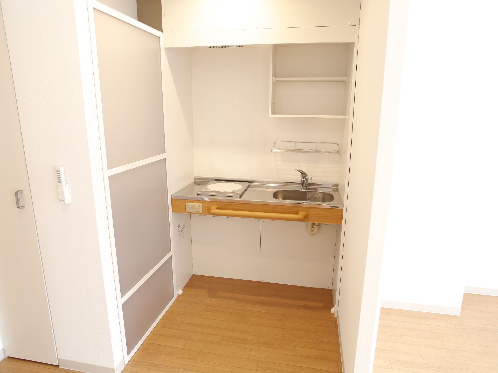 部屋に車椅子に座ったまま作業できるIHヒーター付ミニキッチン。手元で換気扇等のスイッチ操作が可能、動作をサポートする手すりも付いている。