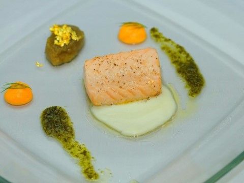 ガラスの食器に盛り付けられ、周囲にソースと付け合わせが添えられている魚のミキュイ
