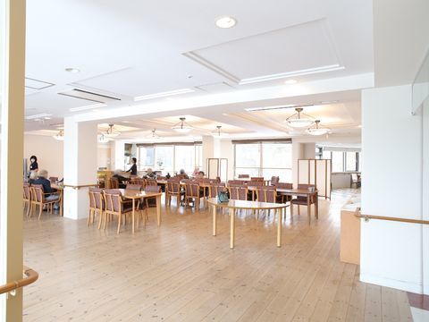 木肌を活かしたフローリングとそれに合わせた木製テーブルが並んだ、広い食堂
