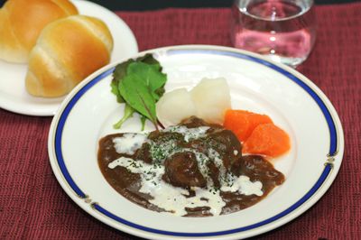 バターロールとルッコラやにんじんを添えたビーフシチュー