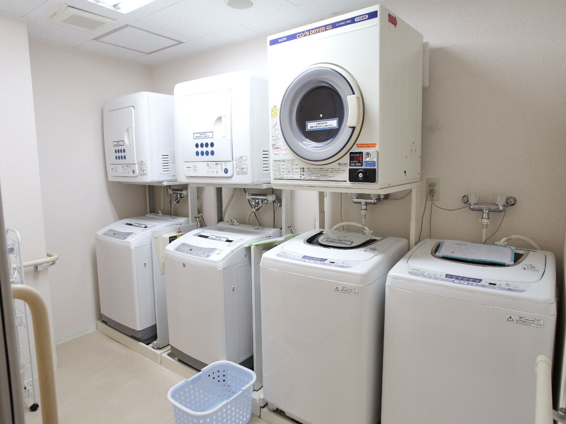 洗濯機が四台に乾燥機が三台置かれている洗濯室。ここの壁のどの面にも手すりがしっかりと完備されている。