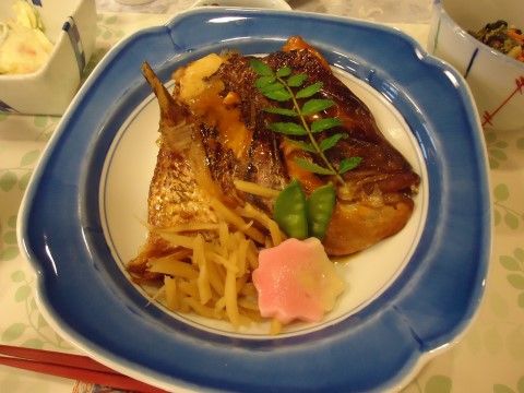 魚の煮付けに緑やピンク、黄色の食材をあしらった食事