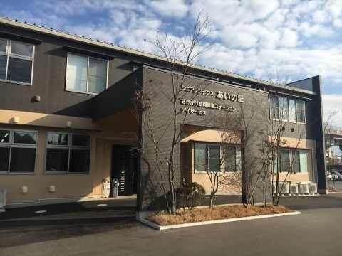 施設の手前には開放的なスペースが確保されている。施設の入口は屋根に覆われており、すぐ近くに草木が植えられている。