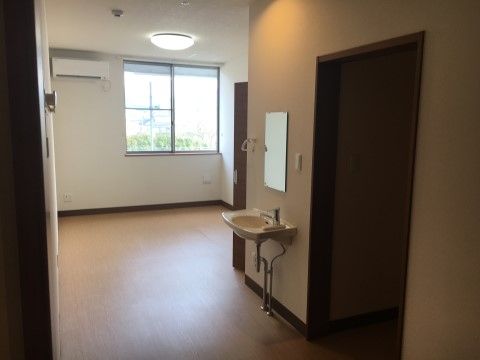 居室内は広々としており、落ち着いた色合いの空間となっている。エアコンが備え付けられているほか、大きめの窓から日の光が差し込んでいる。