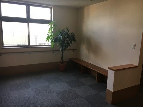 障害物のない広々とした空間があり、その一角に低めのベンチが用意されている。ベンチの隣には、観葉植物が設置されている。