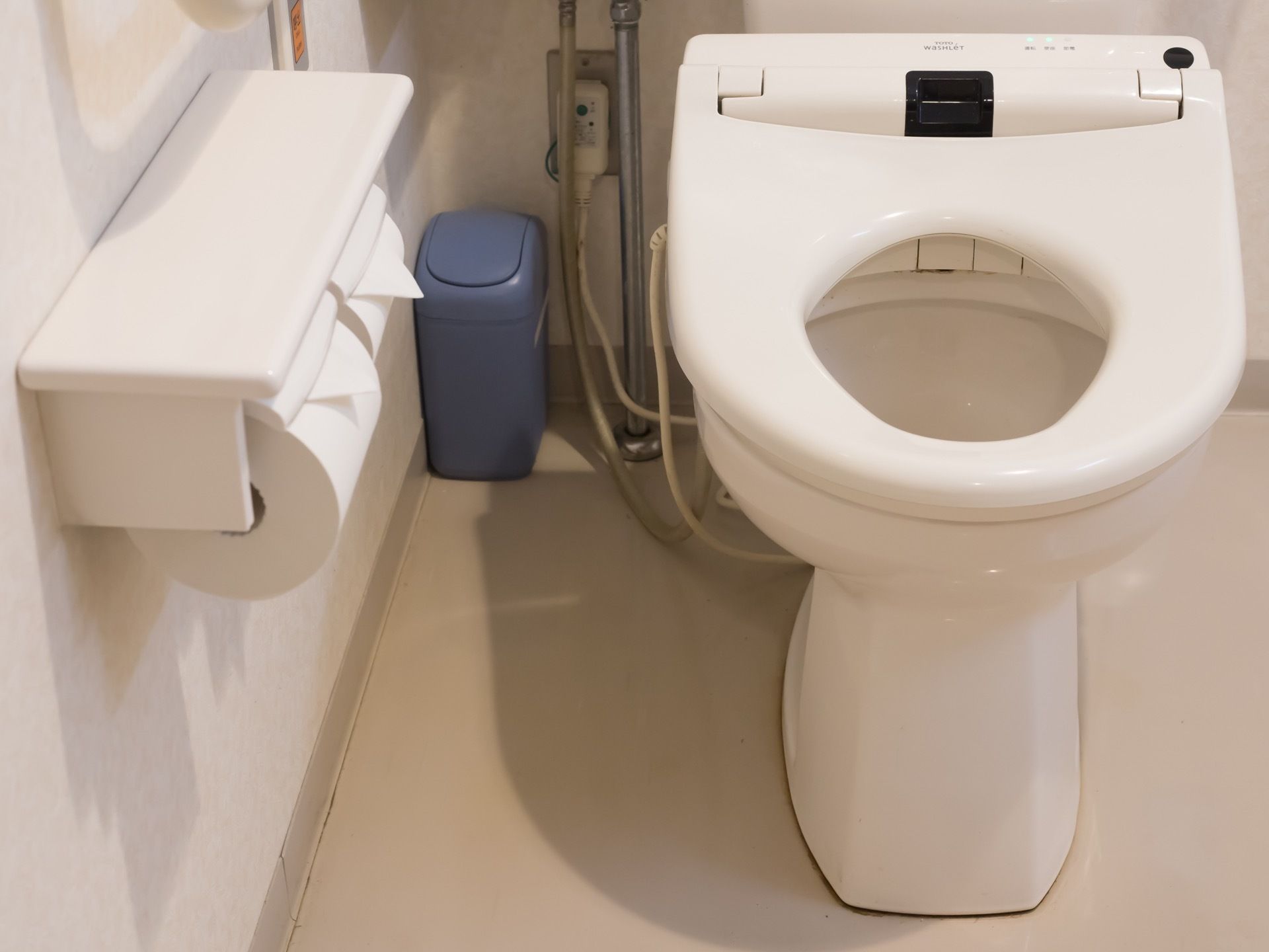 白いトイレが設置されており、壁にはトイレットペーパーが2つセットされている。奥のほうには小さなゴミ箱が置かれている。