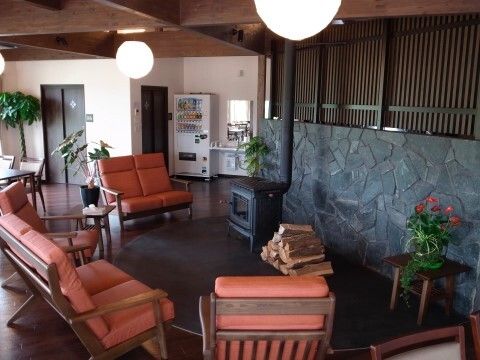 花や観葉植物が飾られた館内にはオレンジの椅子の応接セットが置かれ、奥には自動販売機もある。