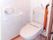 洋式トイレの横の壁にトイレットペーパーホルダーとＬ字型の手すりが設置されている。扉はスライド式となっている。