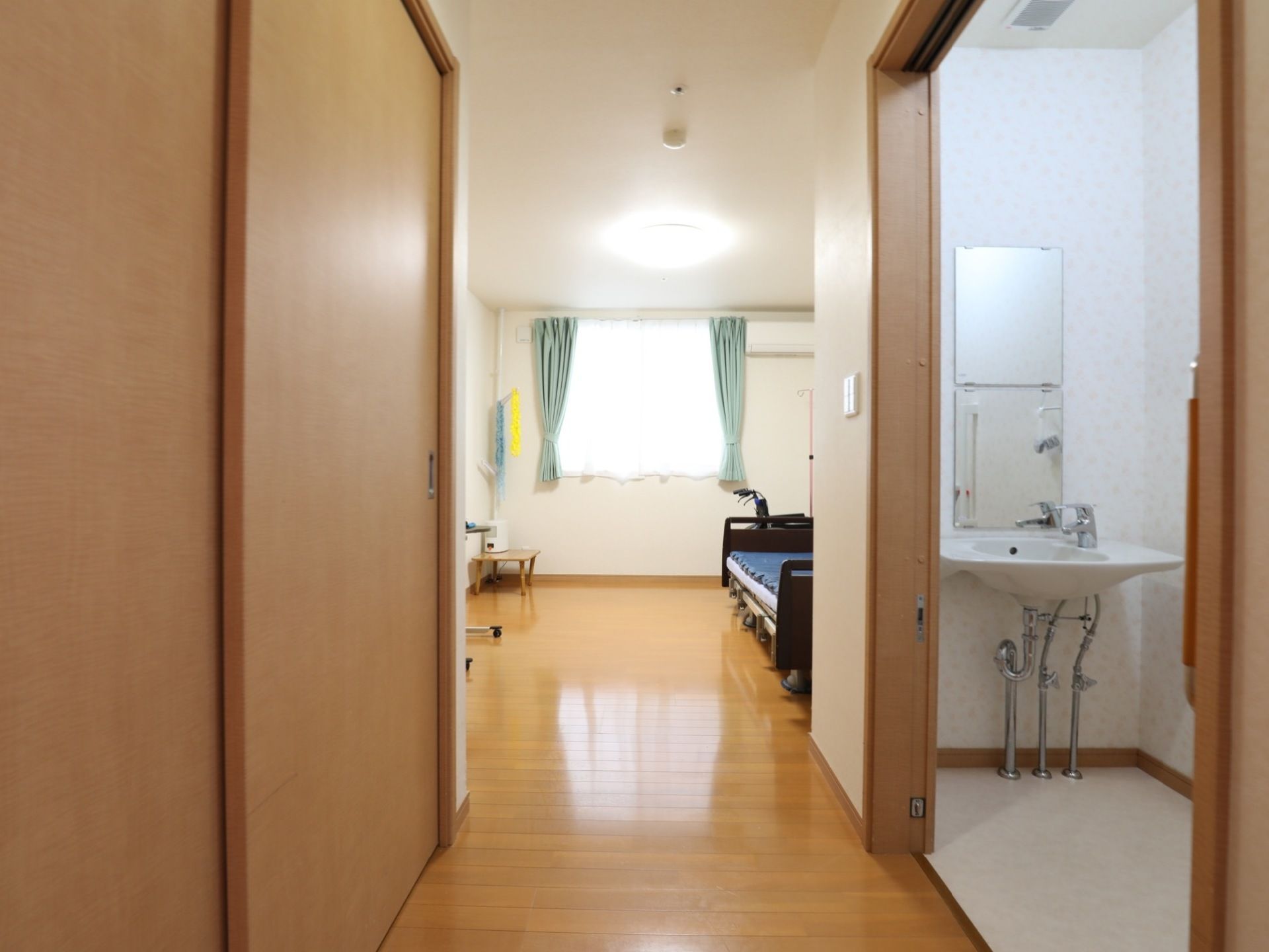 奥行きのある居室である。部屋の右には洗面台、左には収納スペースがある。突き当たりの窓は大きく、日当たりが良い。