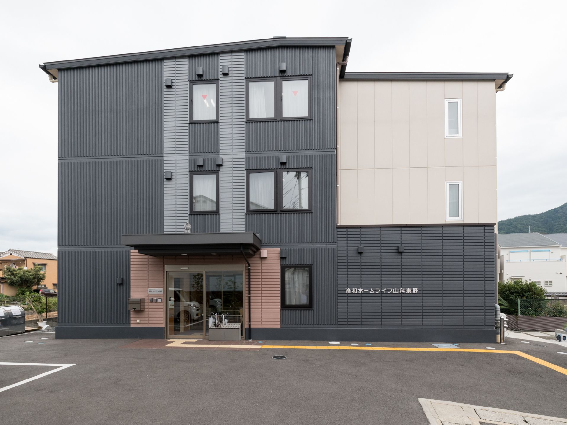 広い敷地に3階建の施設が建っている。目の不自由な方に配慮して、駐車場から施設の玄関まで誘導ブロックが設置されている。
