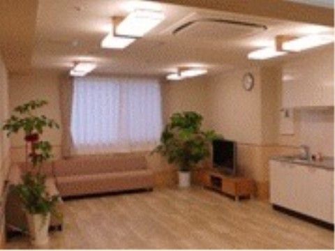 ベージュ系で統一された空間に優しいピンクのソファーが置かれている。部屋の壁際には、火を使わないオール電化タイプのキッチンがある。