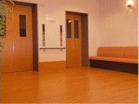 ドアが茶色いエレベーターが２基並んでいる。エレベーターホールの壁際には、長椅子風のソファーが置かれている。
