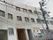 3階建ての施設があり、そばには電柱が立っている。1階部分の窓には柵が付いており、安心して過ごすことができる。