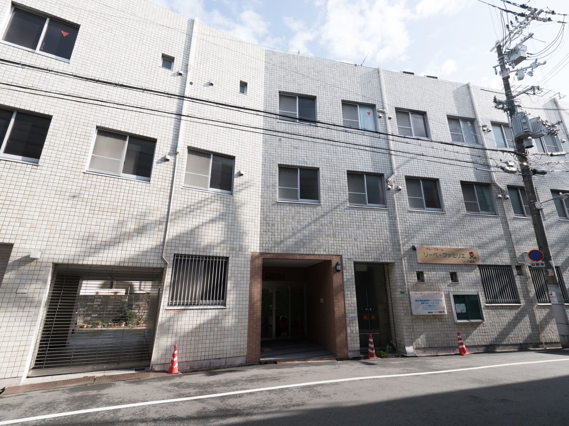 施設は３階建てである。外壁には施設名が書かれた看板が取り付けられている。入口の周りの壁は茶色いタイルが貼られている。