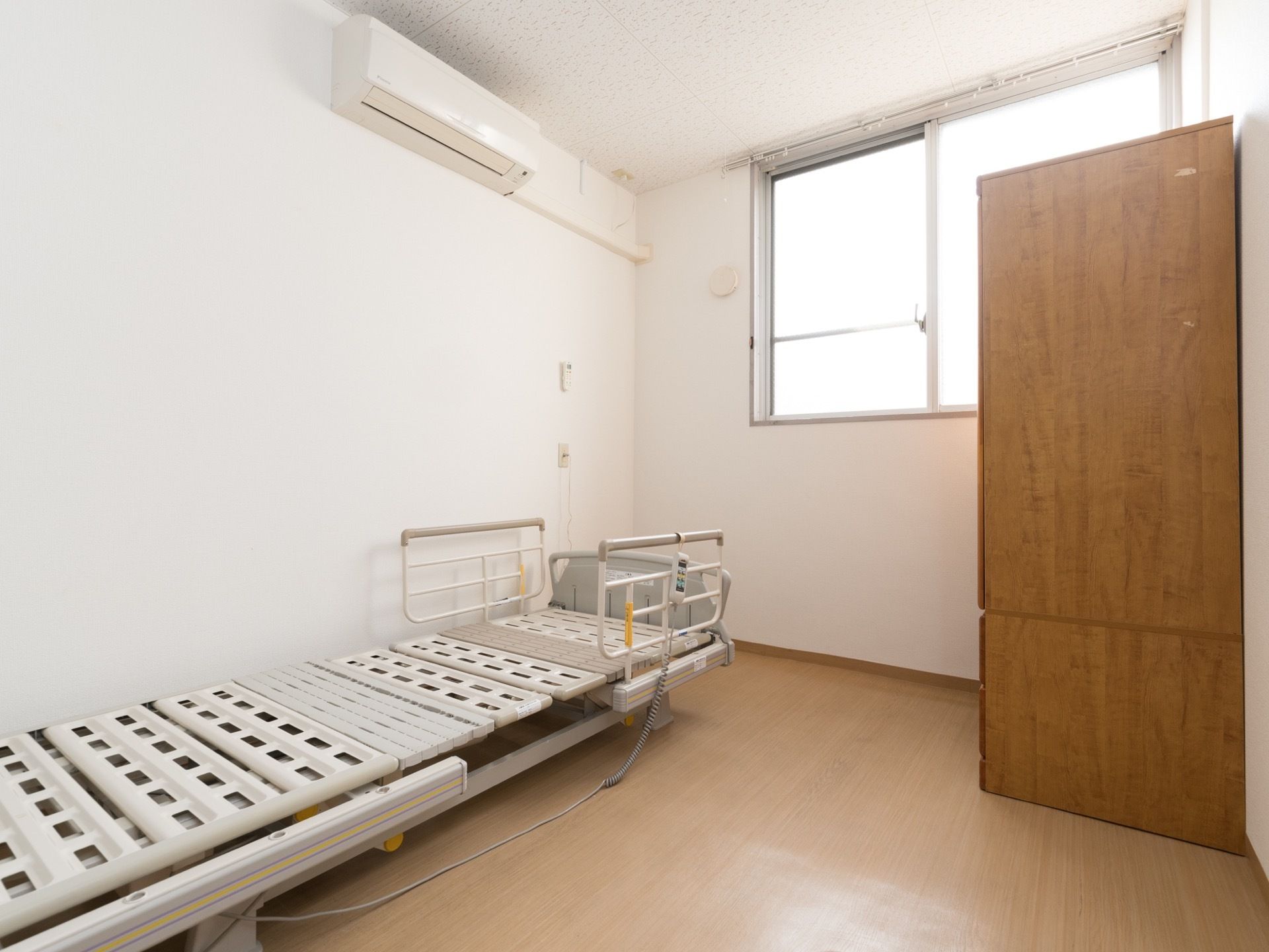 居室には大きな窓がある。壁にはエアコンが設置されている。ベッドはリクライニング式のものが用意されている。
