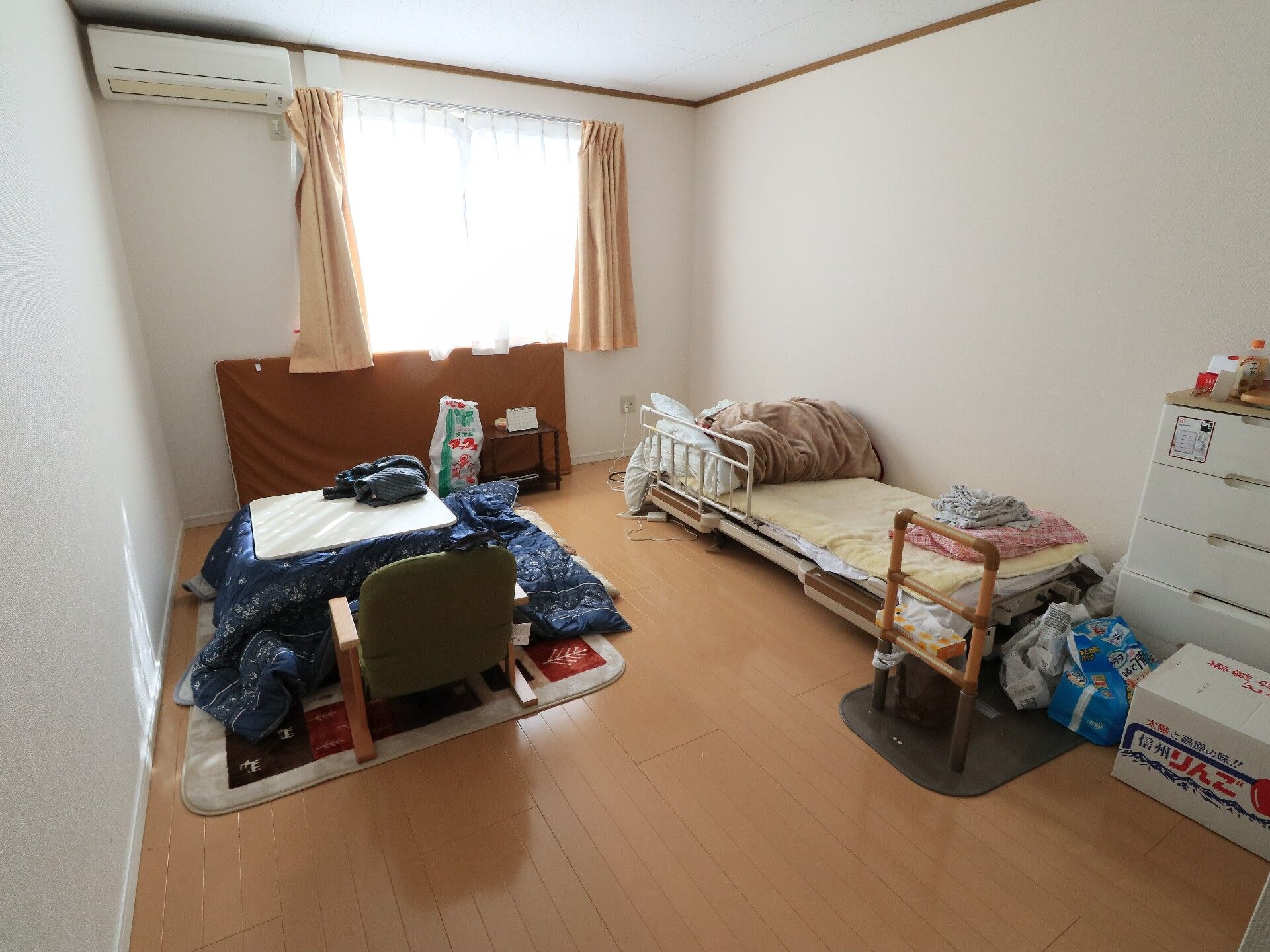 手すり付きの高さの低いベッドとこたつのある、温かみのある個室