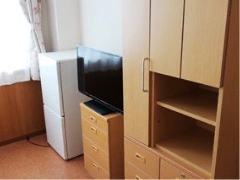 腰高窓の下には腰板が張られている。システム家具は引き戸と引き出しのついた収納スペースとオープンになった棚がある。