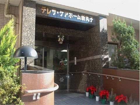 玄関には金色で施設名が表示されている。入口まではスロープになっており手すりがついているため、どなた様でも快適に施設へ入れる。
