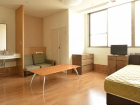 十分な広さを備えた居室にはテーブルやソファが置かれ、来訪者様が一緒でもゆったりと過ごしていただける。洗面所も設置されている。