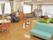 バリアフリーの部屋で、歩行用平行棒がおいてある。マッサージチェアーがおいてある。ソファー、テーブル、椅子がおいてある。