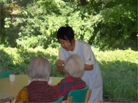 ご入居者様のお話を、腰をかがめて同じ目線で聞いているスタッフ
