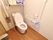 白を基調とした清潔感があるトイレにはポールタイプの棚が取り付けられ、壁には手すりとナースコールが設置されている。