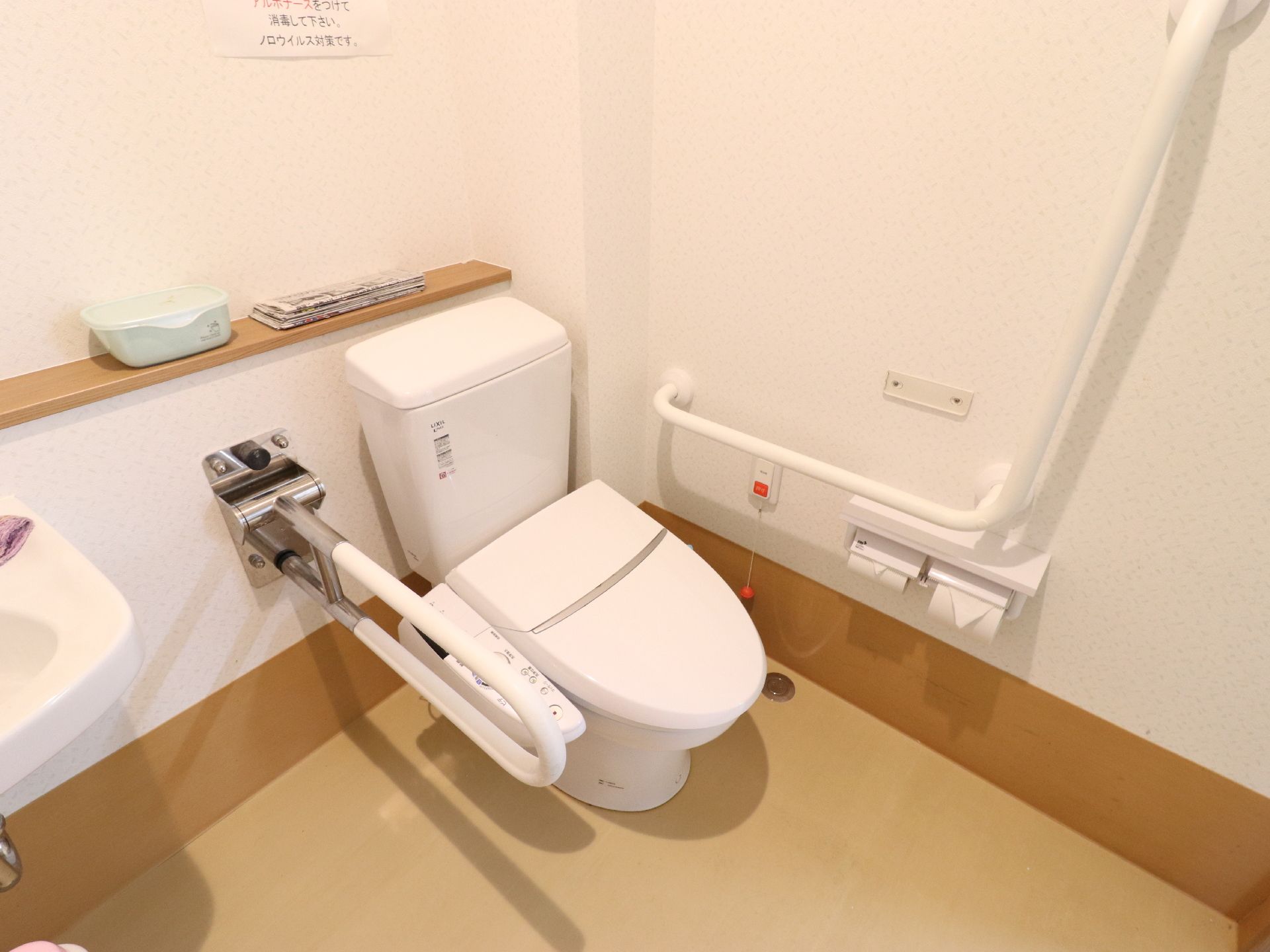 ゆったりとしたスペースがある清潔感のあるトイレ。便器の両わきには手すり、壁にはナースコールが設置されている。