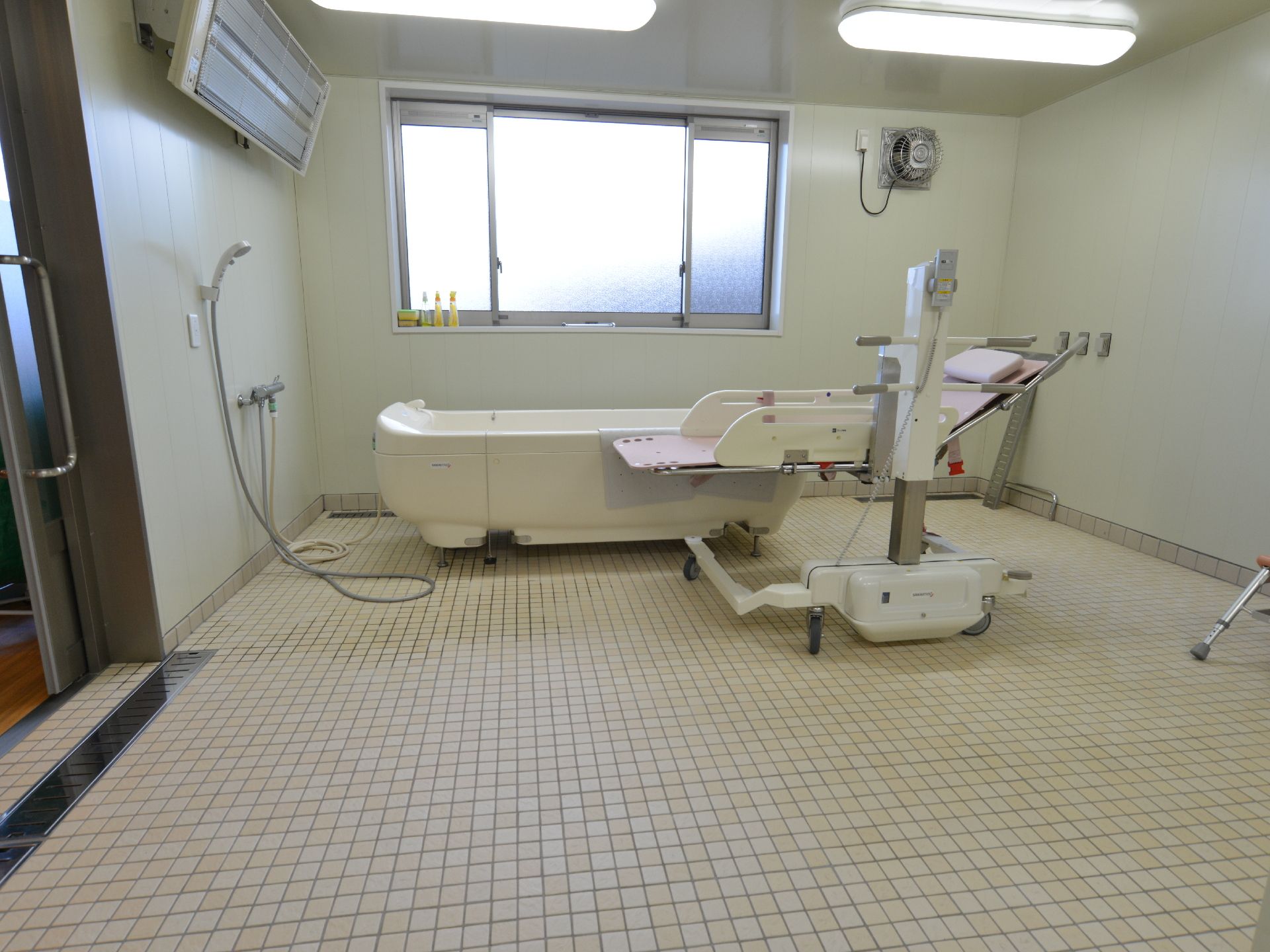 施設には介護浴槽が設置された専用の浴室もある。広い部屋に窓があり窓際に介護浴槽が置かれている。壁にはシャワーもある。