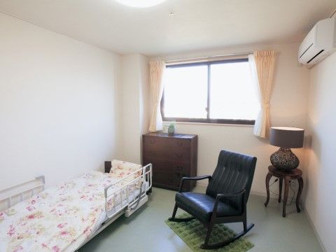 アンティーク風の家具や椅子、スタンド用ランプシェードが置かれた部屋である。入居者様の好みのお部屋に仕上がっている。