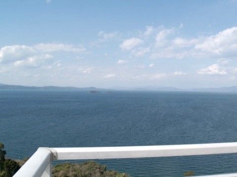 テラスから見た風景である。白い柵の向こうには紺碧の海が続いている。海の向こうには陸地も見える。とても開放感のある場所である。