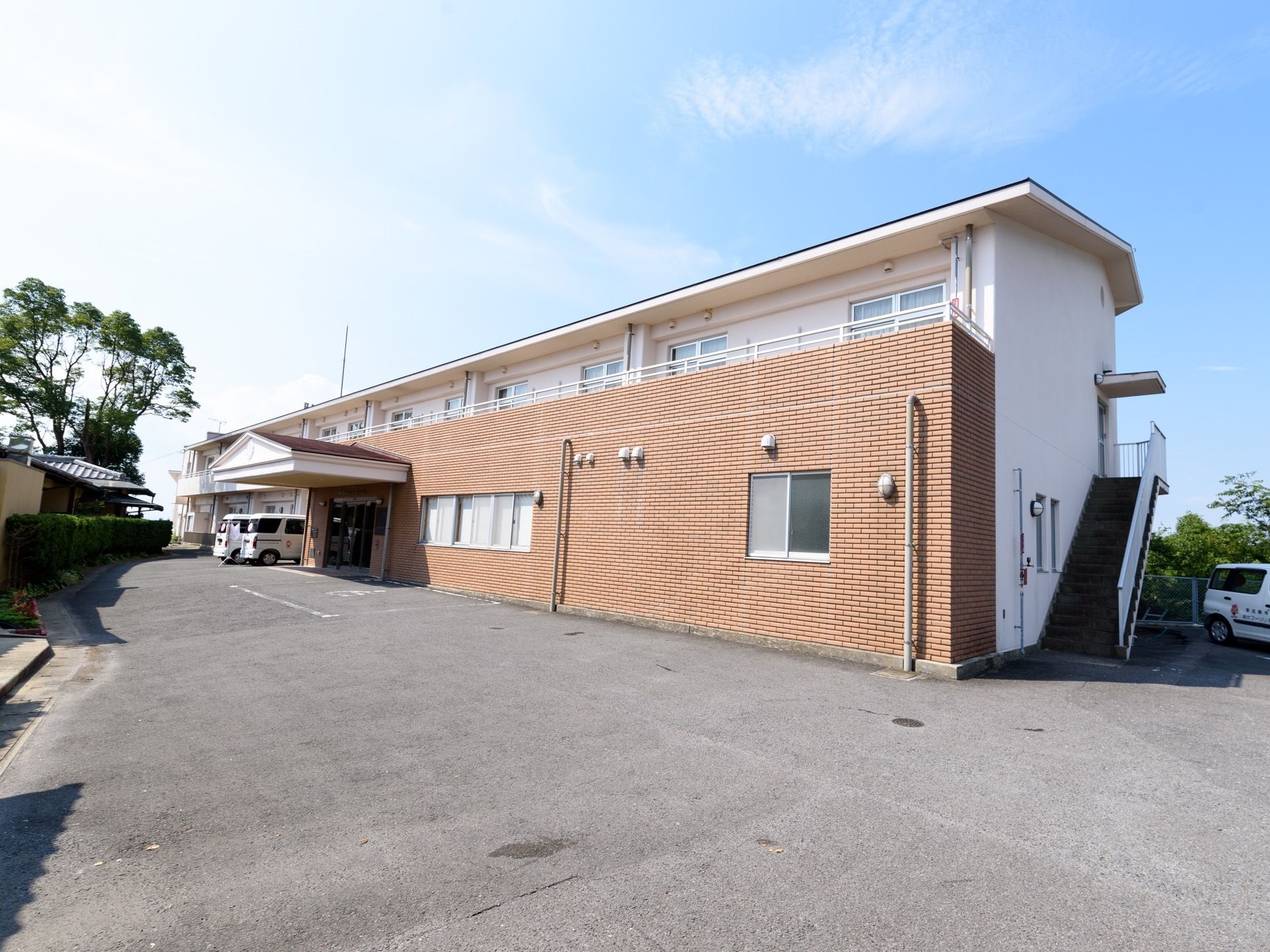 広い敷地に、幅の広い施設が建てられている。白を基調とした建物で、正面部分はレンガ調のデザインである。