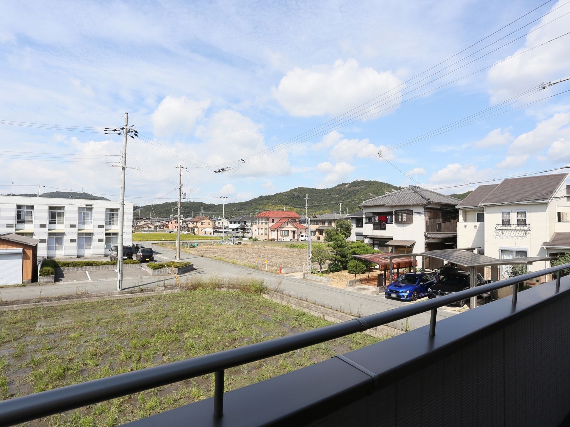 ベランダからは周辺の景色を眺めることができる。田んぼや畑の中に、新しい住宅がまばらに建てられてはじめている。