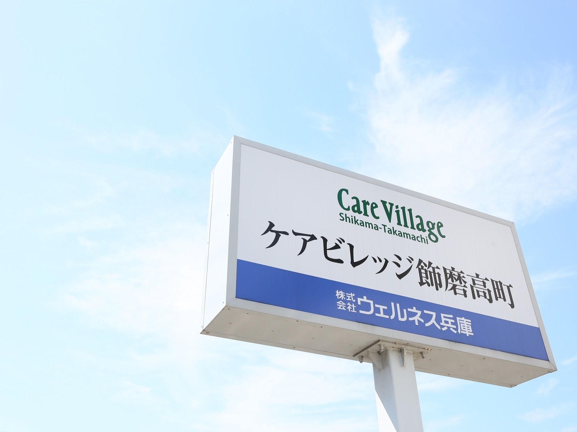 施設には、道路から見やすいように大きな看板が立てられている。金属製のポールの上に取りつけられ、施設名と運営会社の名前が入っている。