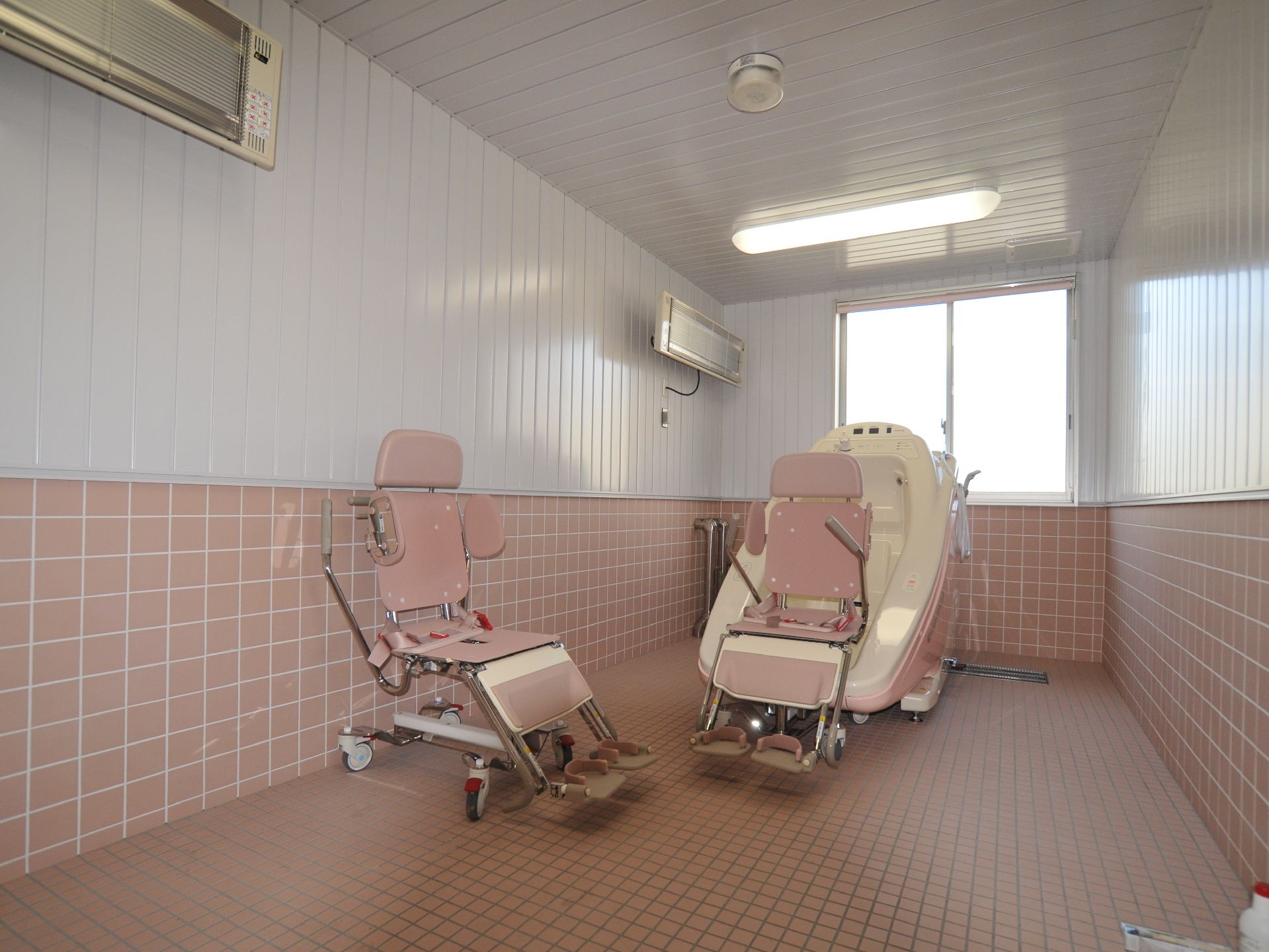 介護用ユニットバスが一台置いてある。入浴用椅子が2客置いてある。一脚はユニットバスにセットしてある。