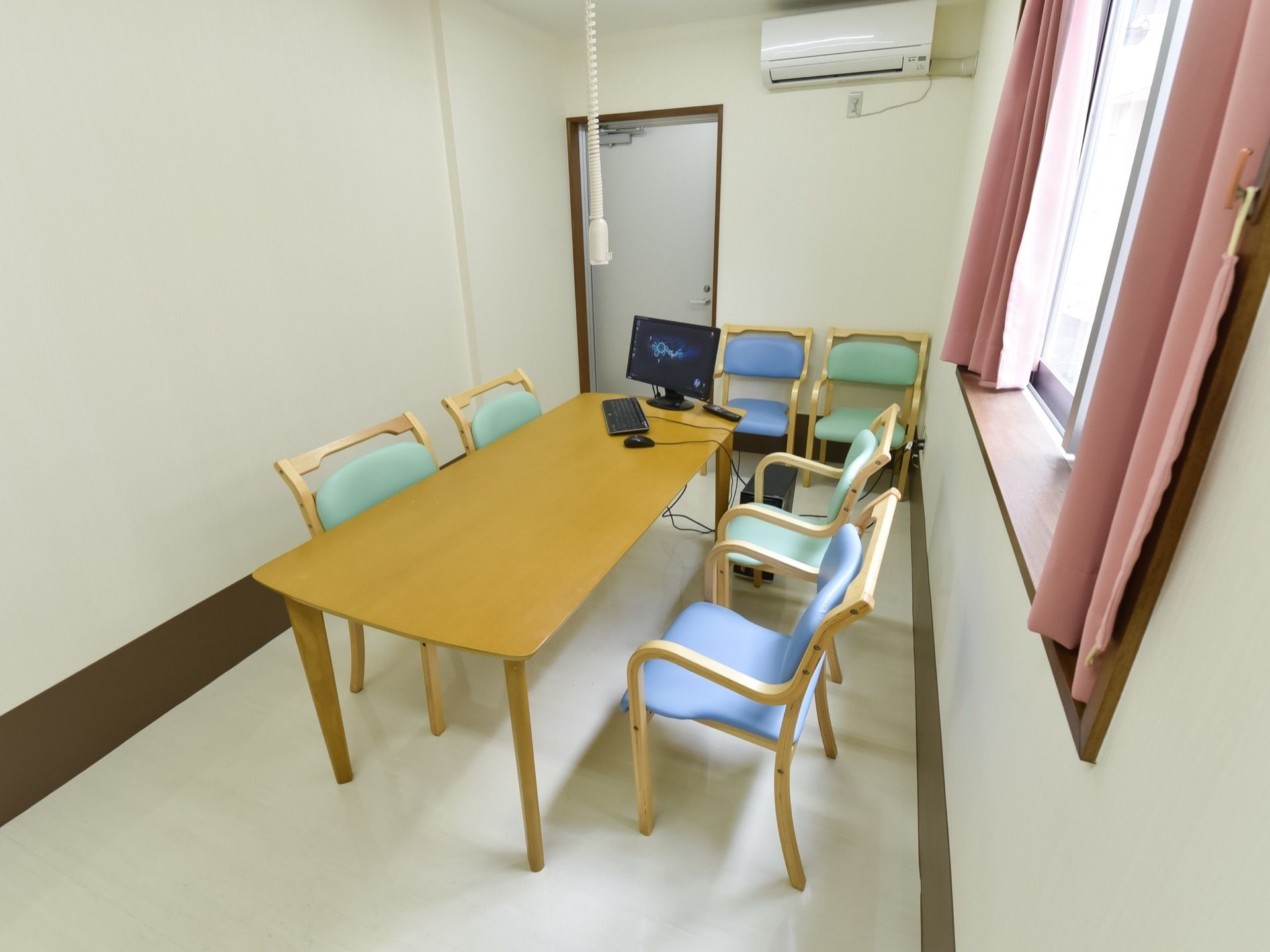 部屋の中に、テーブルセットが置かれている。テーブルの上に、パソコンが置かれている。右手に窓があり、カーテンが付いている。