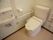 トイレ個室内。温水洗浄便座付きトイレで、便座横に操作ボタンが付いているタイプである。手洗い場も併設されている。