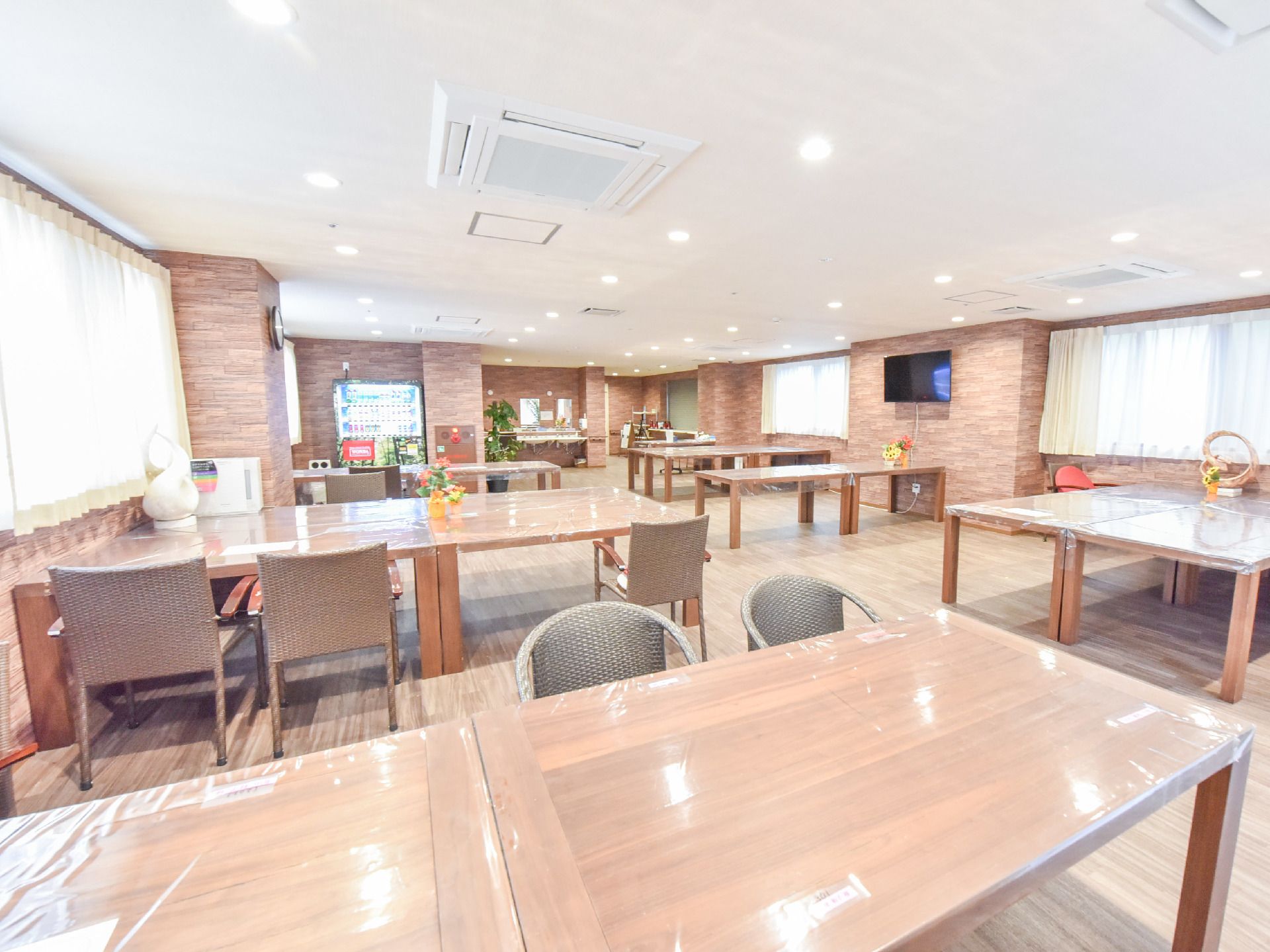 レンガ調の壁から半島状になるようダイニングテーブルを配置し、中央に通路を設けた部屋
