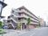 施設建物の外観。パイプ型の手すりのある非常階段のような通路が暗褐色の外壁に沿って張り巡らされているのがわかる。