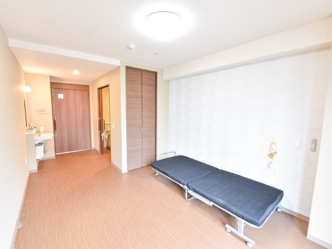 引き戸式のドアがある個室の廊下側。収納クローゼットが設置され、手洗い台と個人用トイレがあるのが見える。