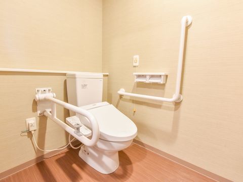 個室に設備として用意されたトイレの内部。壁から伸びた手すりとナースコールが介護施設としての特徴を示している。