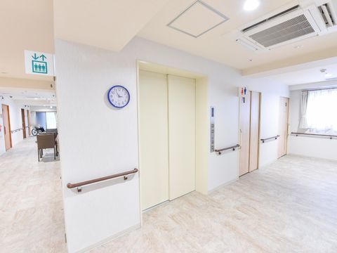 エレベーターの隣には男女共用の引き戸式のトイレがある。また左側には青い縁のアナログ時計が掲示されている。