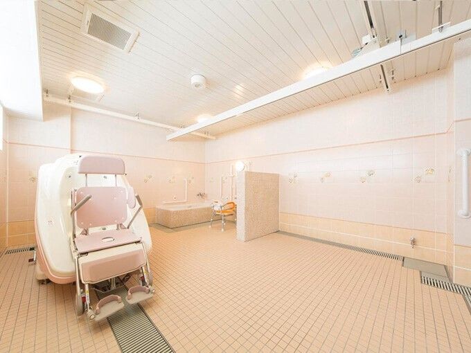 介助用のバスタブが設置してある浴室で、椅子に座ったままの状態でお風呂が楽しめる。シャワー横に緊急時ブザーがある。