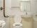 トイレはユニットバスの中に設置されている。ふたつきの便器になっている。トイレットペーパーホルダーの横にナースコールボタンがある。