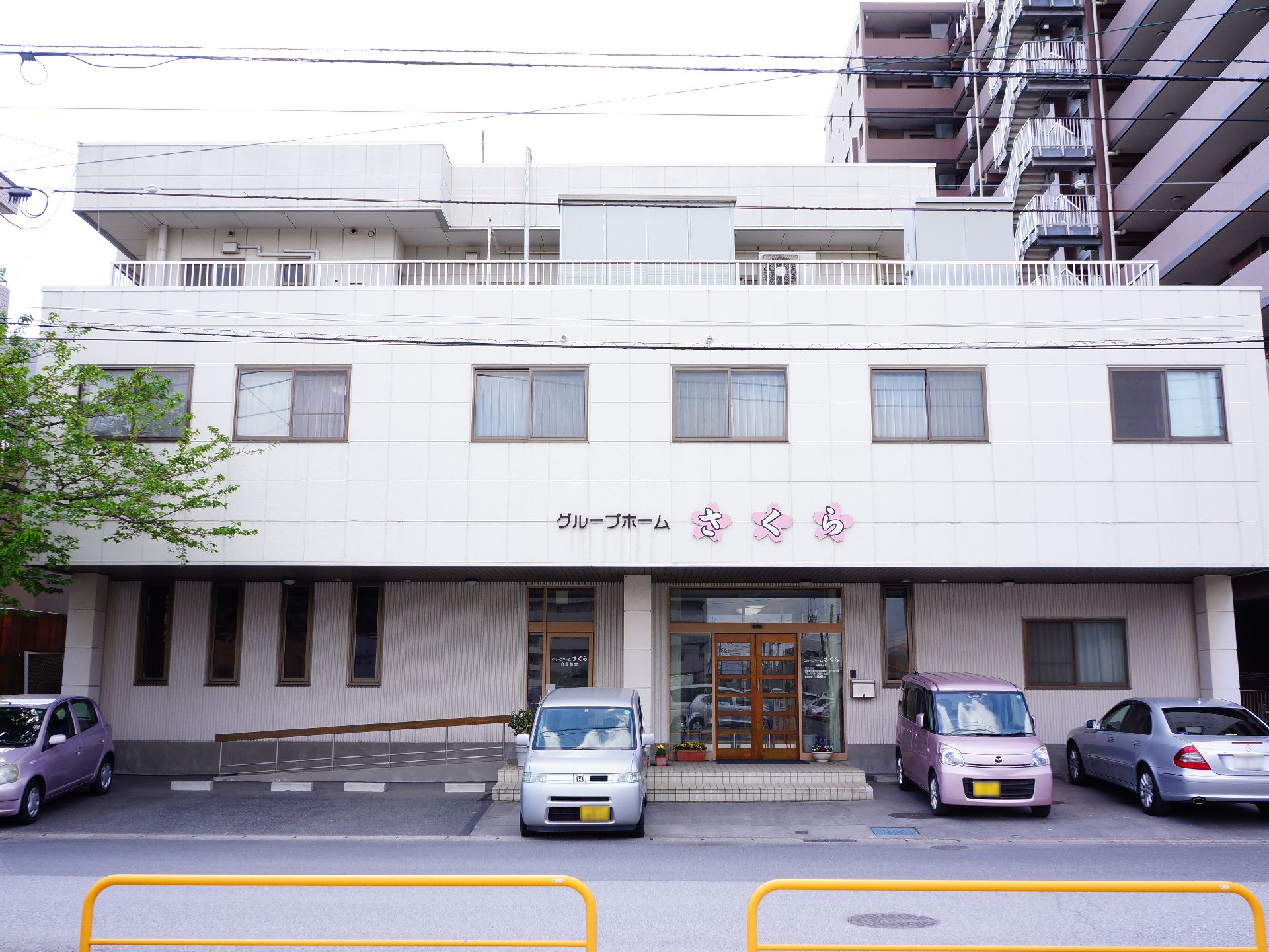 施設の玄関は建物の中央からやや右寄り。前面は2段になっている。左側には手すりが設置されたなだらかなスロープがある。